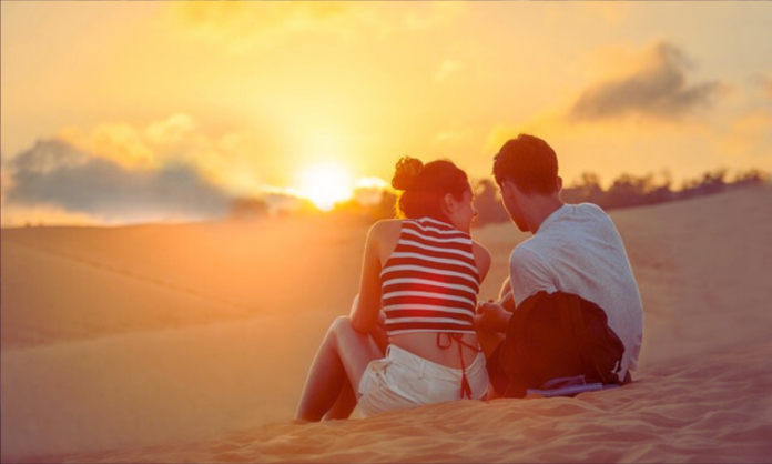 a man and woman sitting on sand
